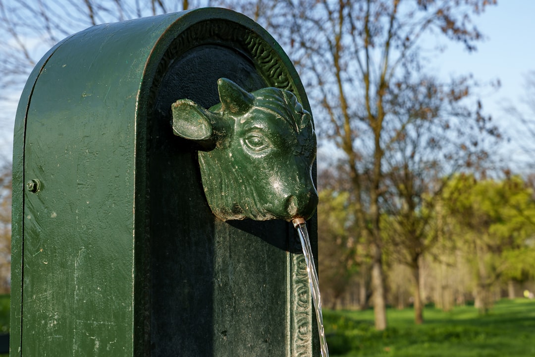 A green fountain shaped like a cow's head outdoors